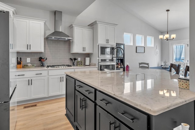 kitchen with decorative backsplash, white cabinetry, a notable chandelier, and wall chimney range hood