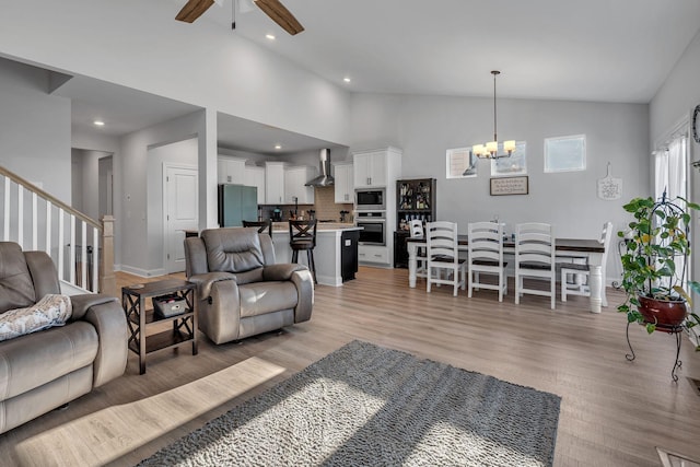 living room with light hardwood / wood-style flooring, high vaulted ceiling, and ceiling fan with notable chandelier