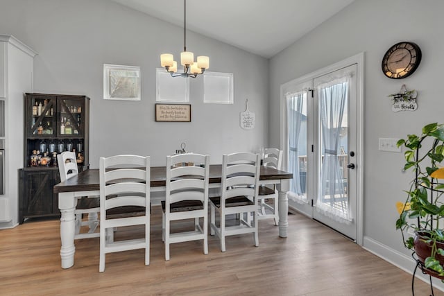 dining space featuring light wood-type flooring, lofted ceiling, and an inviting chandelier