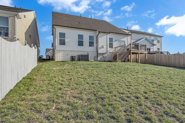 rear view of property with central AC unit and a lawn