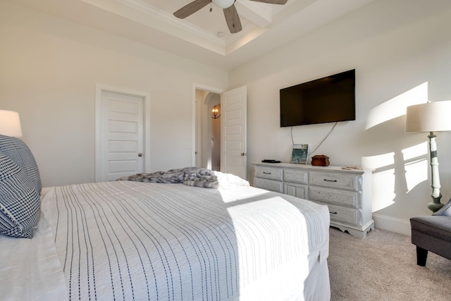 carpeted bedroom with a raised ceiling and ceiling fan