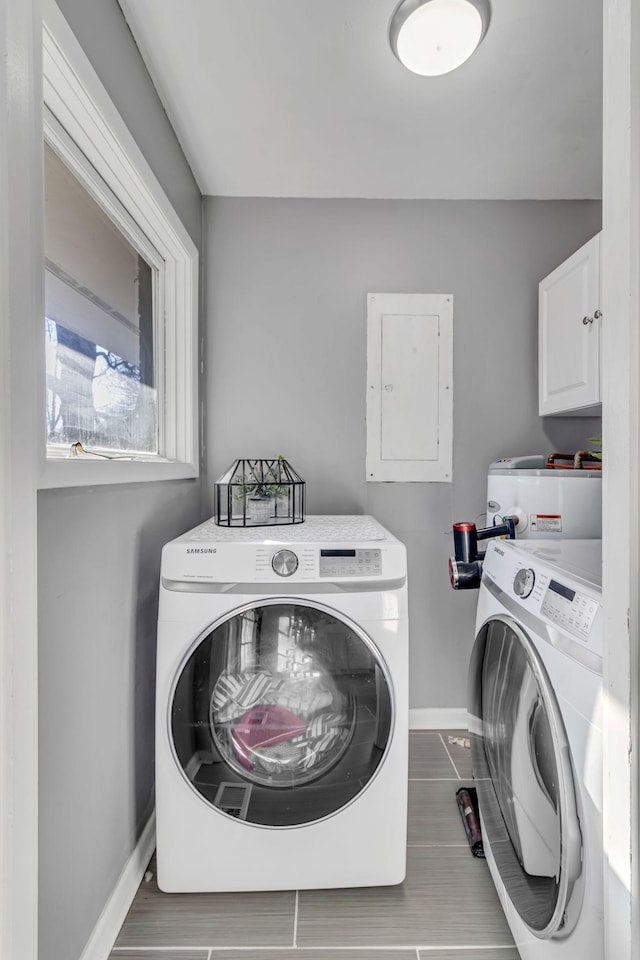 laundry area featuring electric panel, cabinets, dark tile patterned floors, and washer and dryer