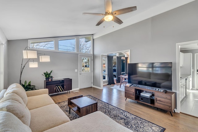 living room featuring ceiling fan, vaulted ceiling, and light hardwood / wood-style flooring