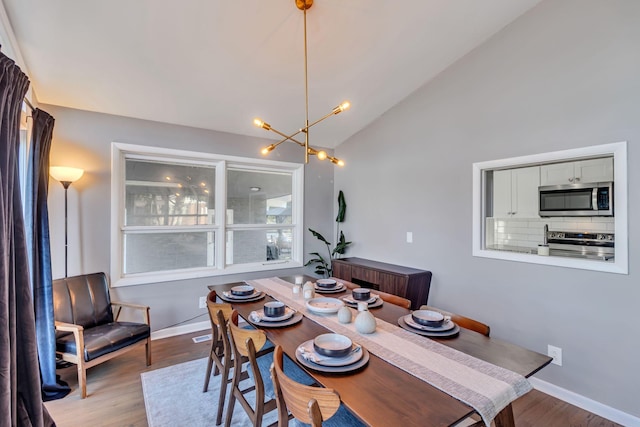 dining space with lofted ceiling, a chandelier, and hardwood / wood-style floors