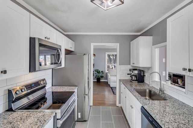 kitchen with stainless steel appliances, sink, white cabinetry, decorative backsplash, and a healthy amount of sunlight