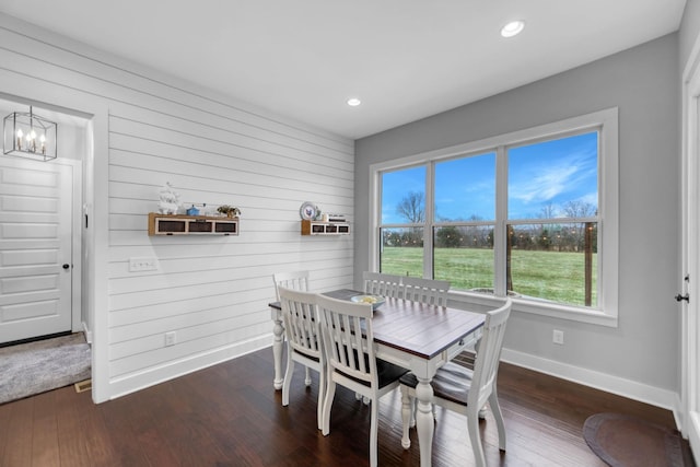 dining space with dark hardwood / wood-style floors and wooden walls