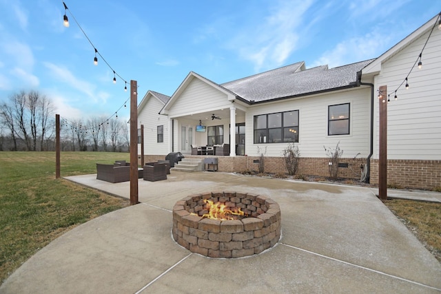 back of property with ceiling fan, a yard, a patio, and an outdoor living space with a fire pit