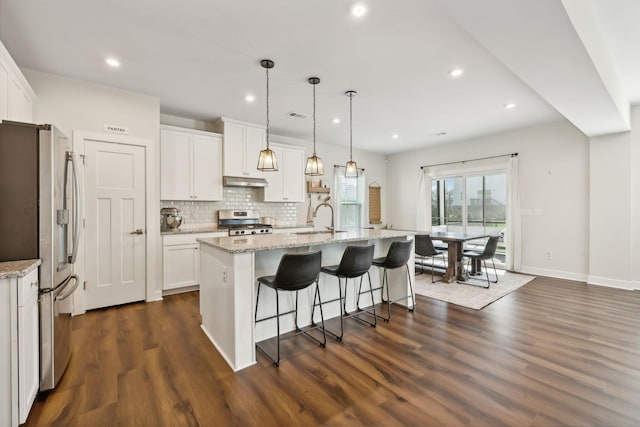 kitchen featuring white cabinets, an island with sink, pendant lighting, and appliances with stainless steel finishes