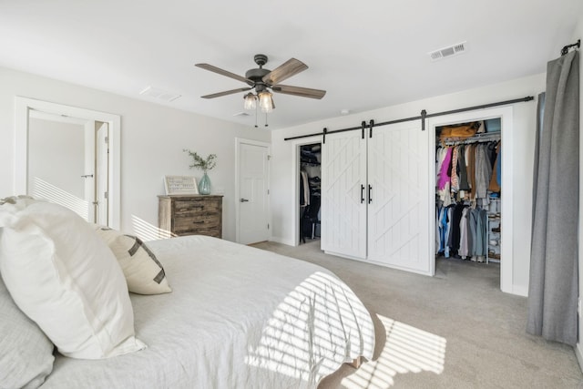 bedroom with light carpet, a barn door, and ceiling fan