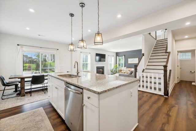 kitchen with white cabinets, sink, stainless steel dishwasher, light stone countertops, and decorative light fixtures