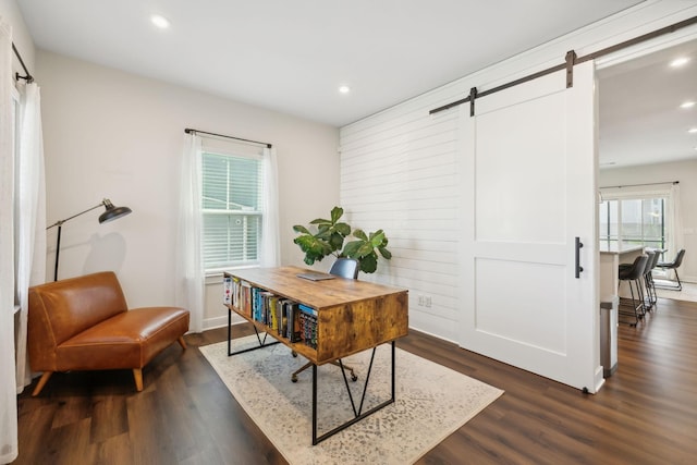 office space with a barn door and dark hardwood / wood-style flooring