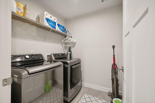 laundry area with separate washer and dryer and light tile patterned floors