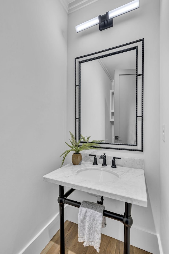 bathroom with hardwood / wood-style floors, crown molding, and sink