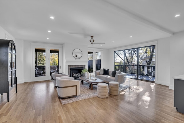 living room with a tile fireplace, light hardwood / wood-style floors, and ceiling fan