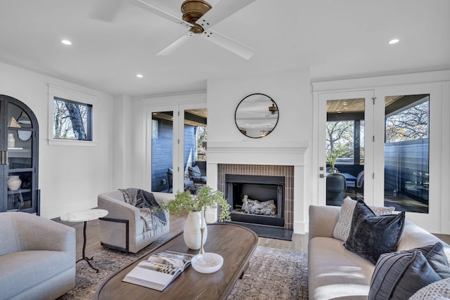 living room with a fireplace, wood-type flooring, french doors, and ceiling fan