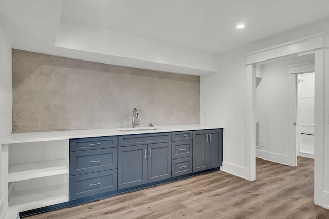 bar with light hardwood / wood-style floors and sink