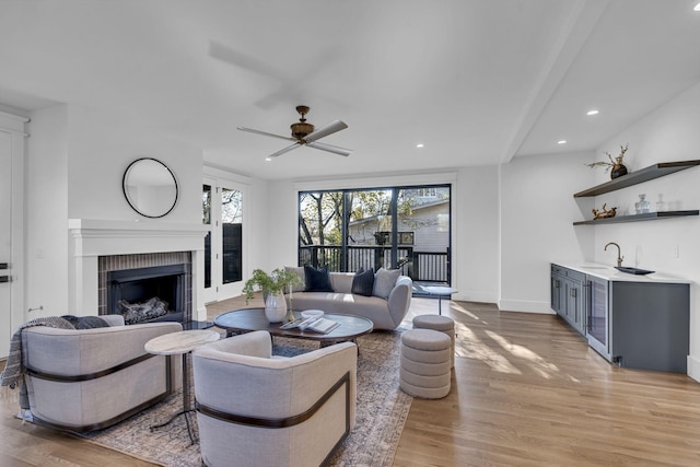 living room featuring ceiling fan, light hardwood / wood-style floors, sink, and beverage cooler