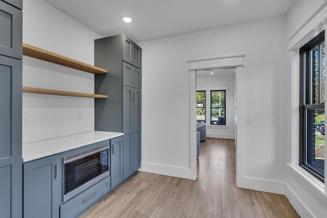 kitchen with light hardwood / wood-style flooring, stainless steel microwave, and light stone counters