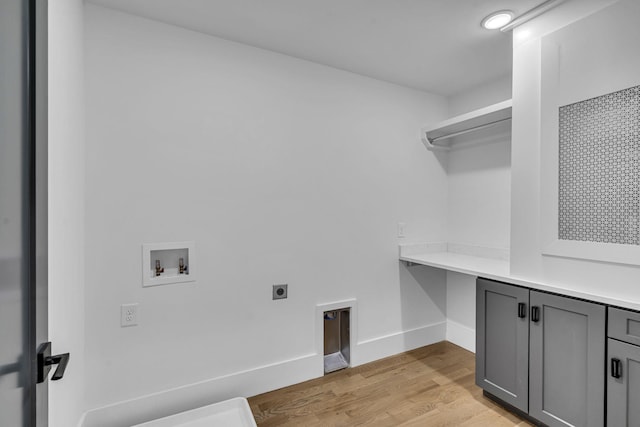 laundry room featuring electric dryer hookup, cabinets, washer hookup, and light wood-type flooring