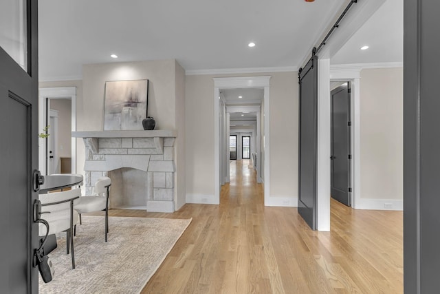 interior space with a barn door, crown molding, and light wood-type flooring