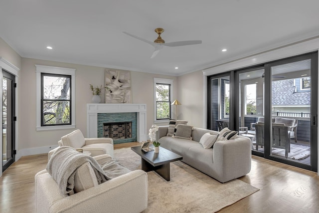 living room featuring a fireplace, light hardwood / wood-style flooring, ceiling fan, and a healthy amount of sunlight