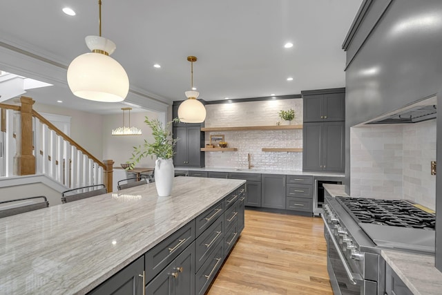 kitchen with decorative backsplash, high end range, gray cabinetry, sink, and pendant lighting