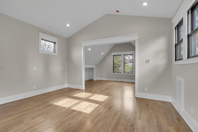 additional living space with light hardwood / wood-style flooring and lofted ceiling