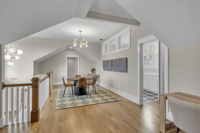 dining room with lofted ceiling, light wood-type flooring, and a chandelier