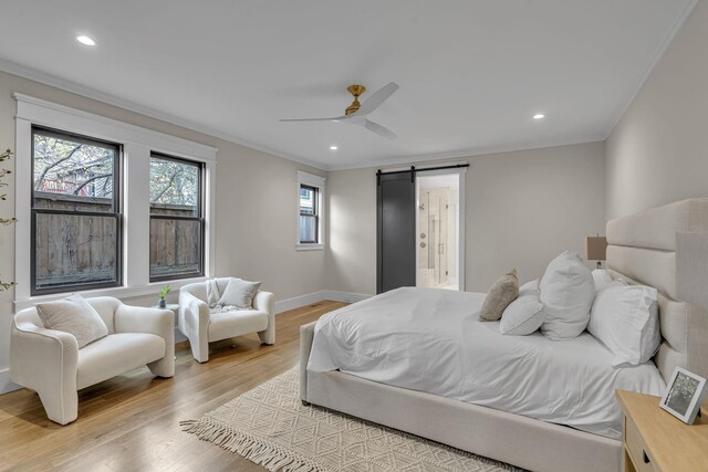 bedroom featuring a barn door, ceiling fan, crown molding, and light wood-type flooring