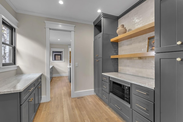 kitchen featuring decorative backsplash, gray cabinets, light stone countertops, ornamental molding, and built in microwave