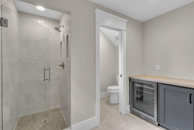 bathroom with tile patterned floors, toilet, a shower with shower door, and wine cooler