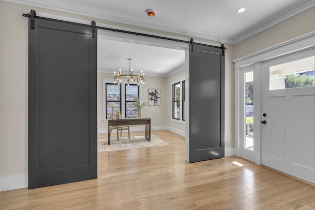 foyer entrance featuring a barn door, crown molding, a wealth of natural light, and an inviting chandelier