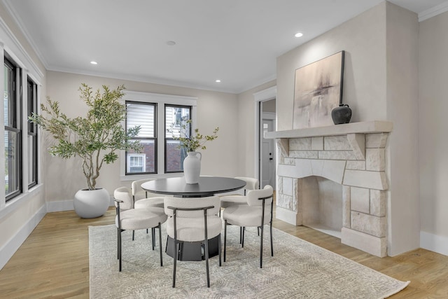 dining space with light hardwood / wood-style floors, a stone fireplace, and ornamental molding