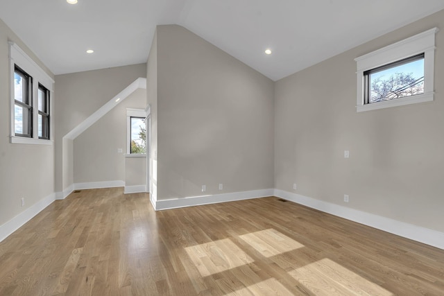 additional living space with light hardwood / wood-style floors, a wealth of natural light, and vaulted ceiling