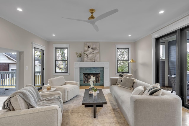 living room featuring ceiling fan, a fireplace, and light wood-type flooring