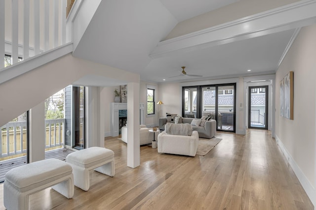 living room with ceiling fan, ornamental molding, a fireplace, and light hardwood / wood-style flooring