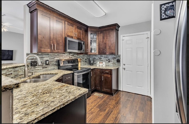 kitchen with stainless steel appliances, sink, dark wood-type flooring, and light stone counters