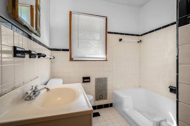 bathroom with vanity, tile patterned floors, a bathing tub, toilet, and tile walls