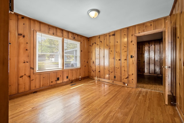 unfurnished room featuring wood walls and light hardwood / wood-style floors