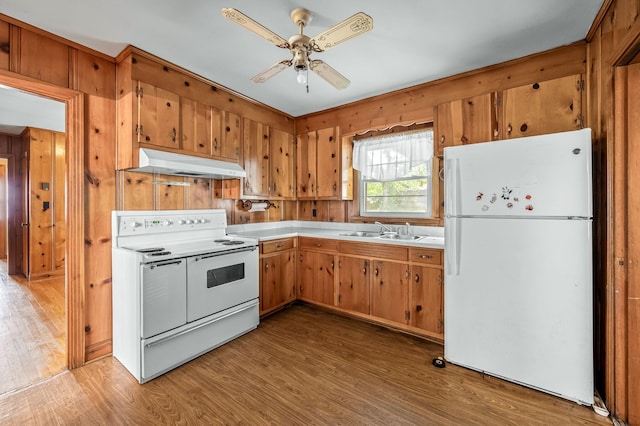 kitchen with ceiling fan, sink, light hardwood / wood-style flooring, white appliances, and wooden walls