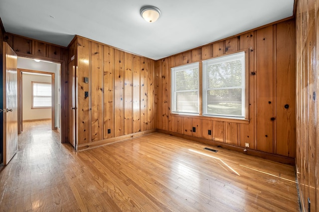 empty room featuring wood walls and light hardwood / wood-style floors