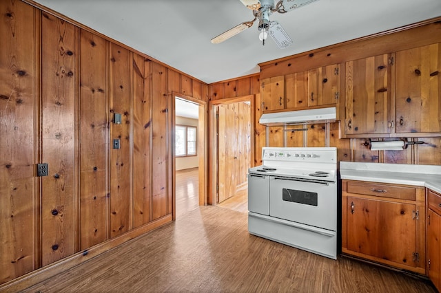 kitchen featuring ceiling fan, light wood-type flooring, white electric stove, and wooden walls