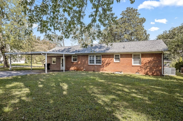 back of property with a carport and a yard