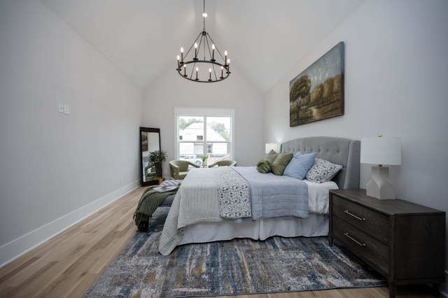 bedroom with light wood-type flooring, high vaulted ceiling, and an inviting chandelier