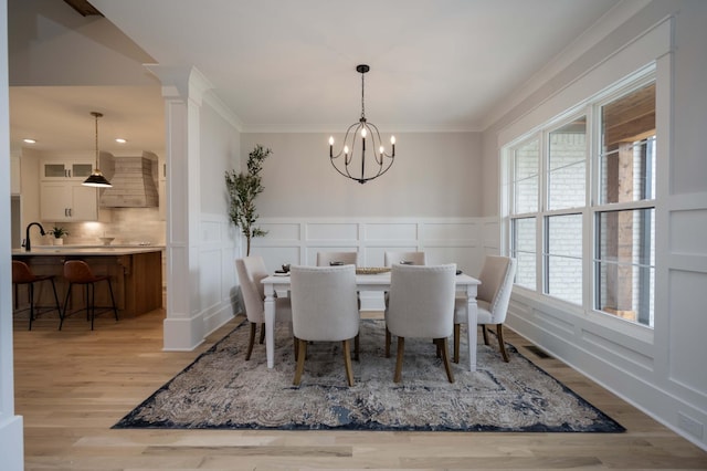 dining area with crown molding, a chandelier, and light hardwood / wood-style floors