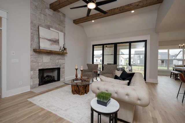 living room featuring ceiling fan with notable chandelier, light hardwood / wood-style floors, a fireplace, and lofted ceiling with beams