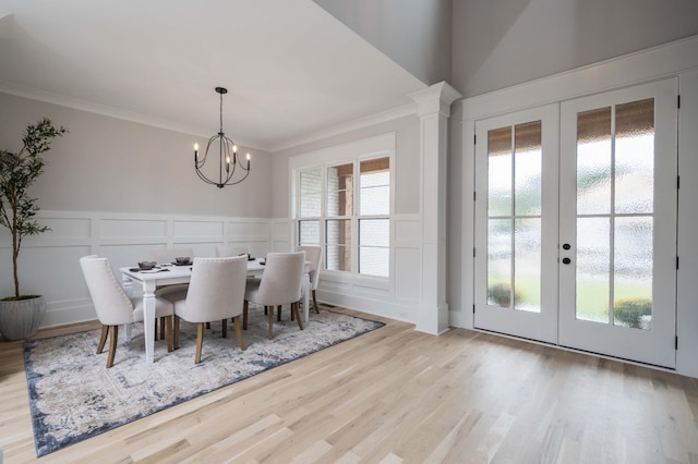 dining area with crown molding, french doors, light hardwood / wood-style floors, and a notable chandelier