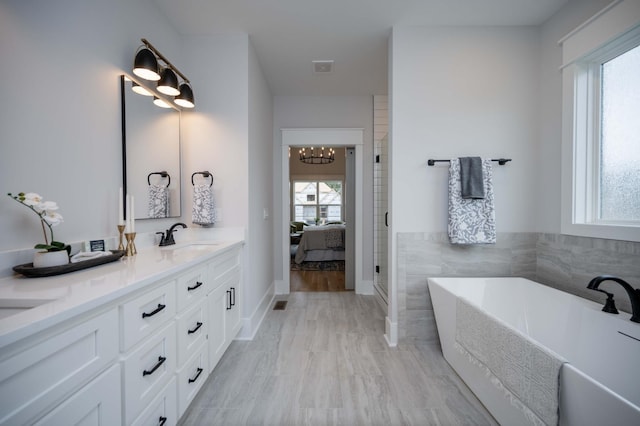 bathroom featuring a chandelier, vanity, and a tub