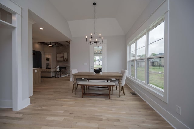 dining space with a chandelier, lofted ceiling, and light hardwood / wood-style floors