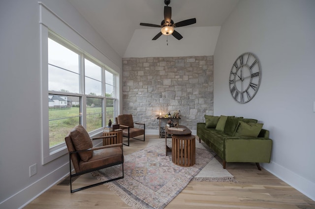 living room with ceiling fan, light hardwood / wood-style flooring, and vaulted ceiling